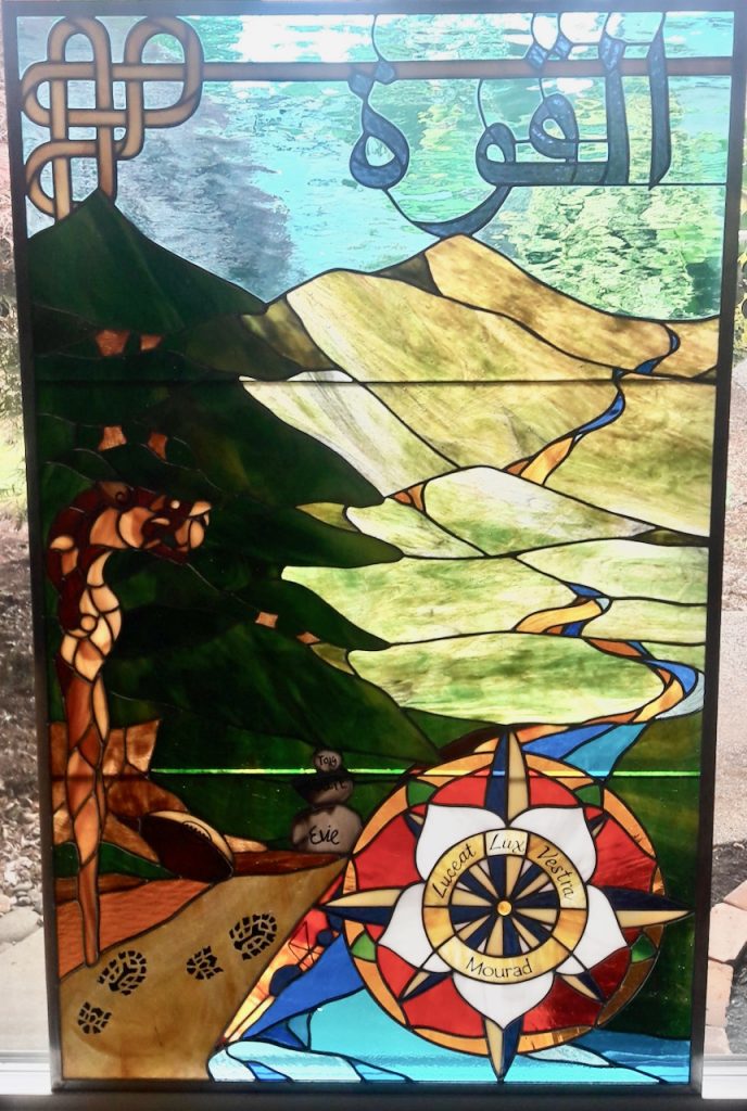 stained glass panel hand painted glass Tudor Rose compass dragon walking stick Lebanese cedar strength in Arabic Celtic knot mountains stream cairn pathway kayak rugby ball aqua green brown red white blue vanilla